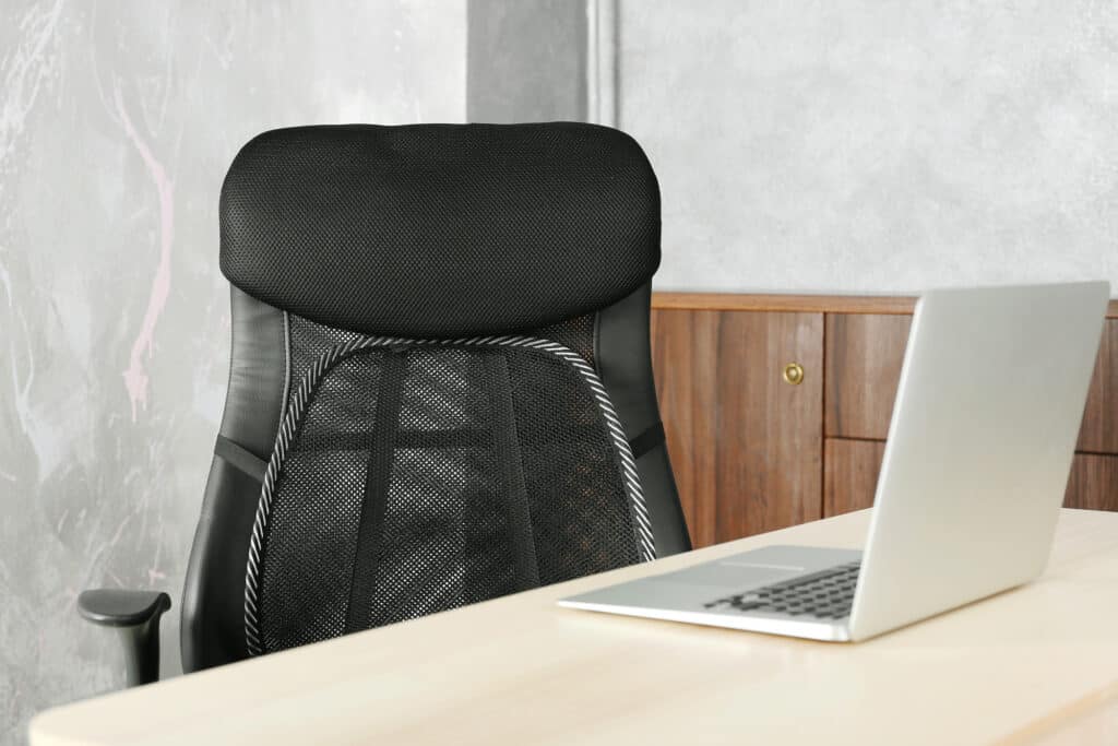 Office chair with mesh for back support and laptop on table, indoors