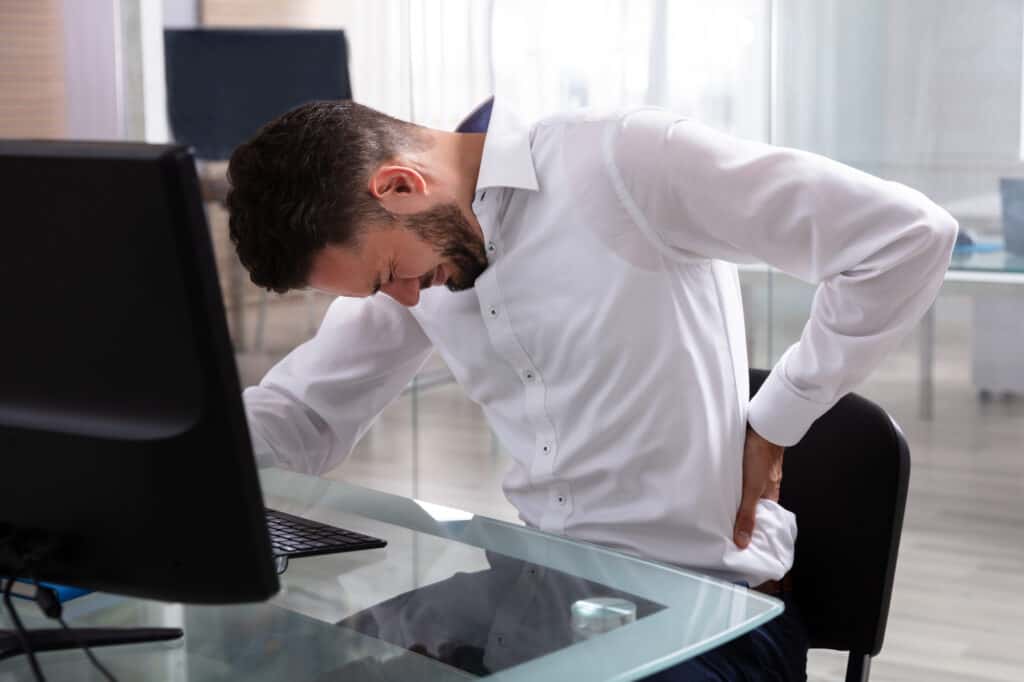 Young Businessman Suffering From Back Pain At Workplace