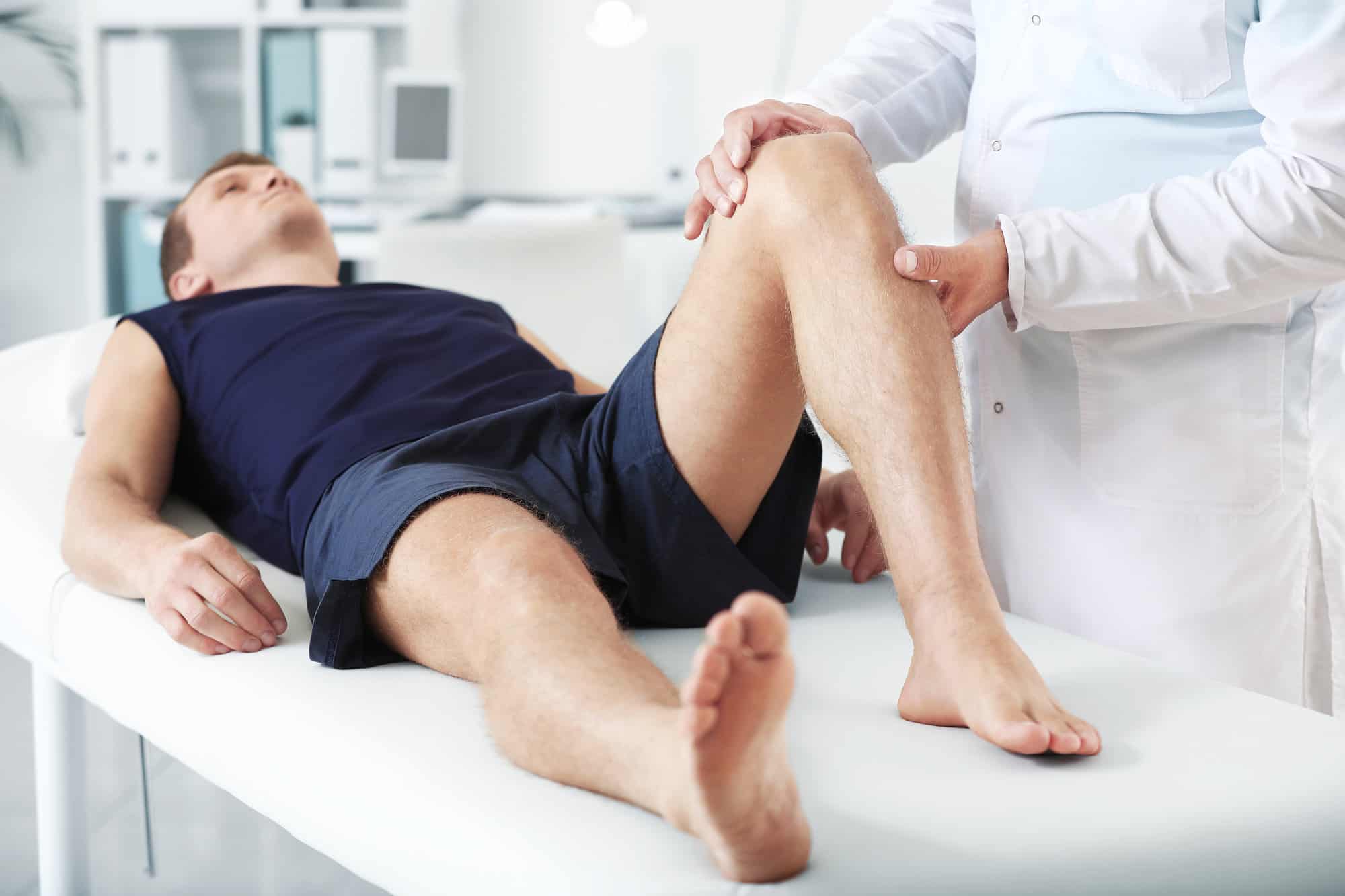 Doctor examining sportsman with joint pain and stiffness in clinic