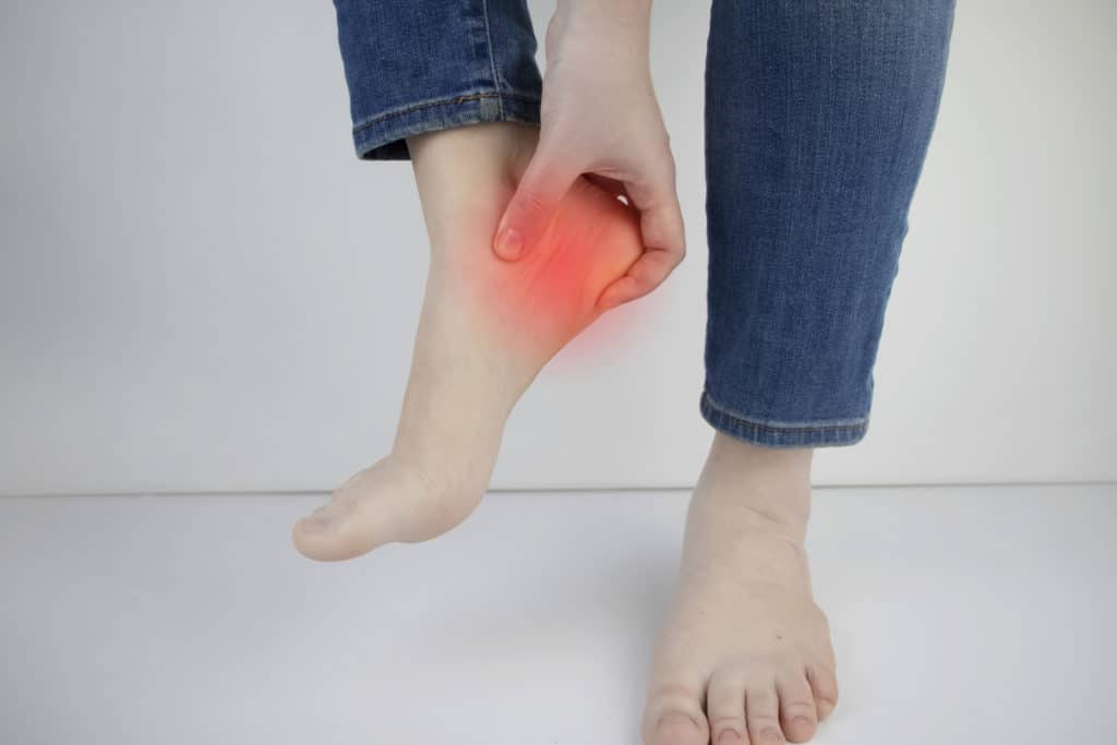 woman holding her ankle in pain due to bursitis