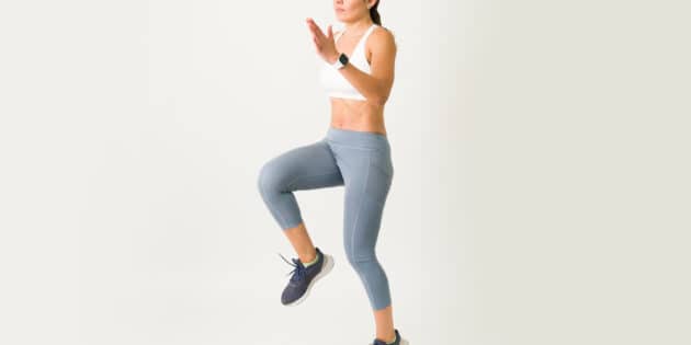 Beautiful caucasian woman jumping and running in place for a high intensity interval training. Female athlete with a strong core doing cardio and HIIT