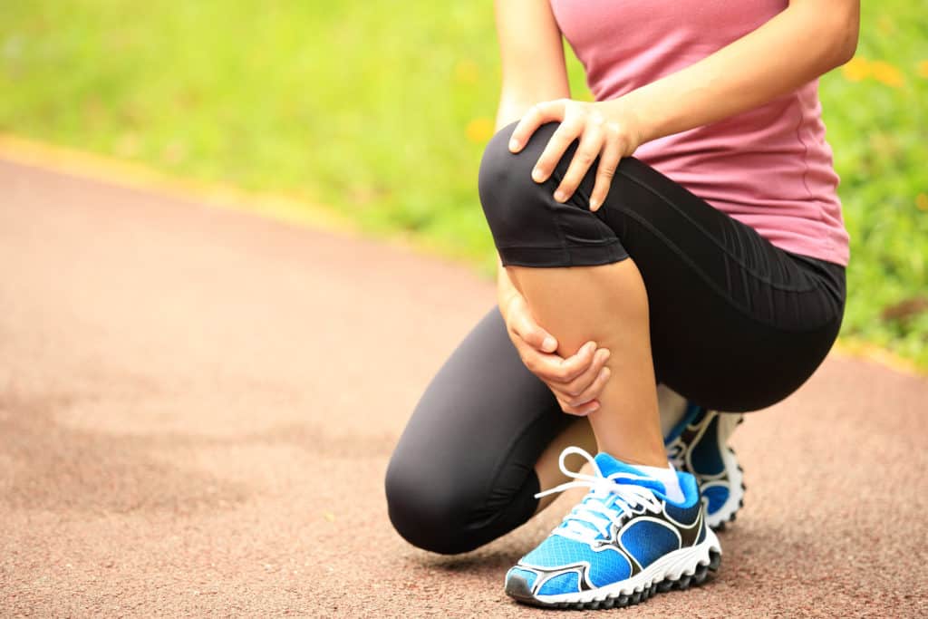 runner holding her knee in pain after injury 