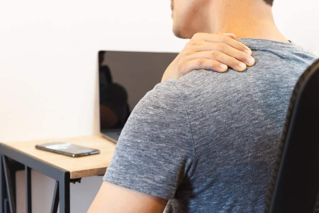 Man with shoulder pain while working on laptop