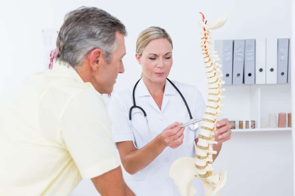 physical therapist showing patient a model of the spine