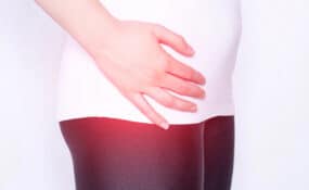 The girl holds on to the hip joint in which pain and inflammation in the thigh