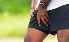 Close up young sport runner black man hold leg has thigh pain while running