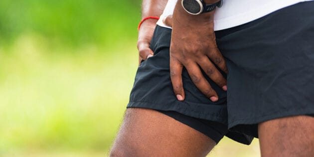 Close up young sport runner black man hold leg has thigh pain while running