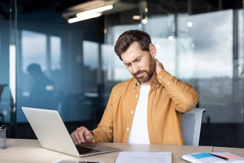Man at work experiencing neck discomfort while seated at a desk
