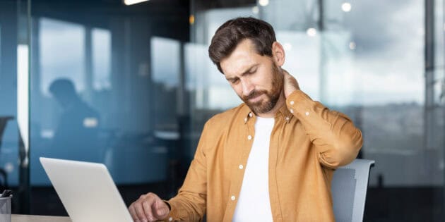 Man at work experiencing neck discomfort while seated at a desk