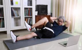 a man doing sit ups on a mat in front of a laptop