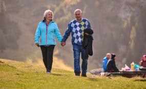 a man and woman holding hands walking on a hill keeping to their fitness goals