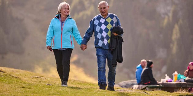 a man and woman holding hands walking on a hill keeping to their fitness goals