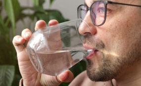 a man drinking from a glass wondering how much water should I drink a day?