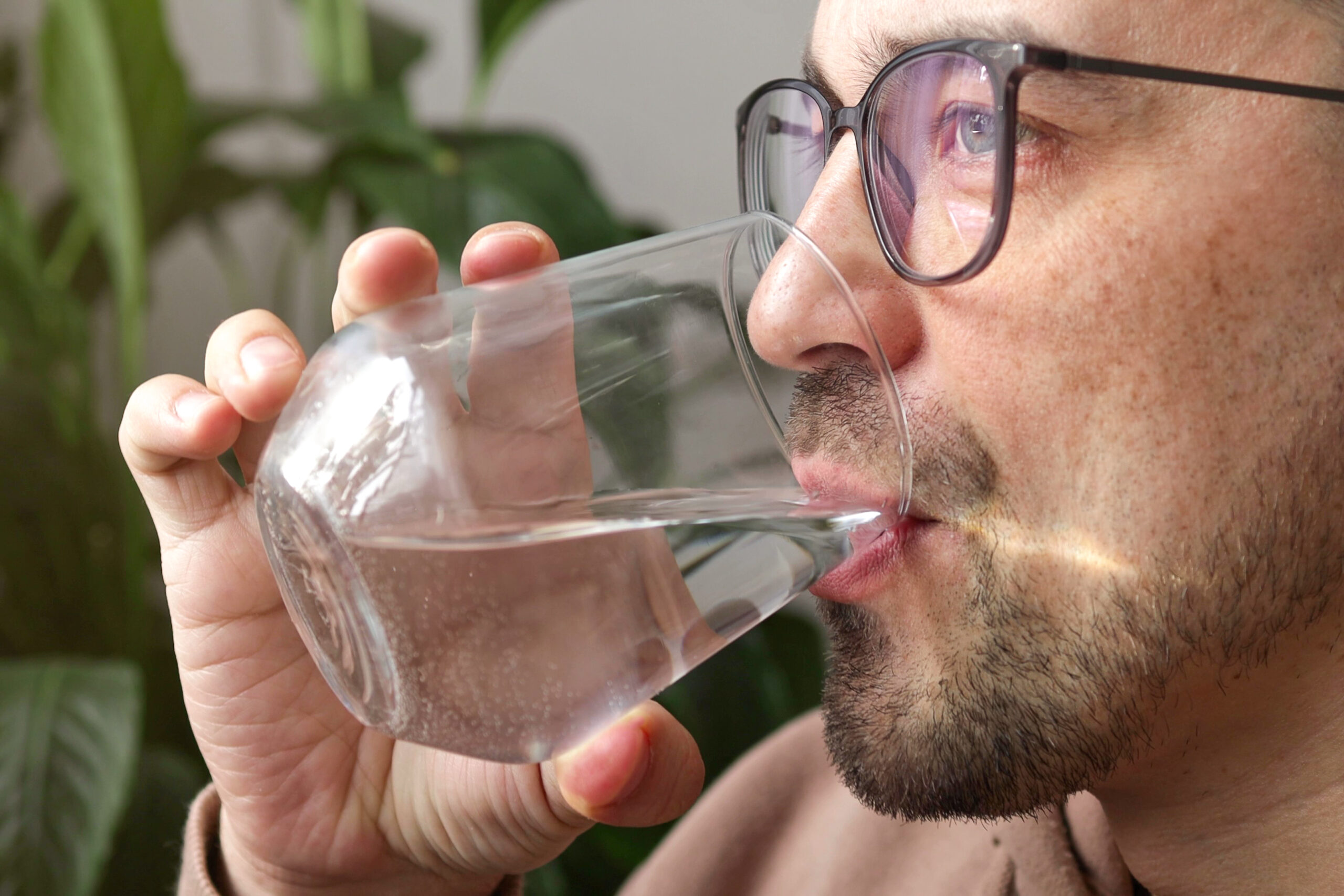 a man drinking from a glass wondering how much water should I drink a day?