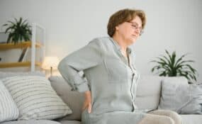 a woman sitting on a couch with her chronic back pain