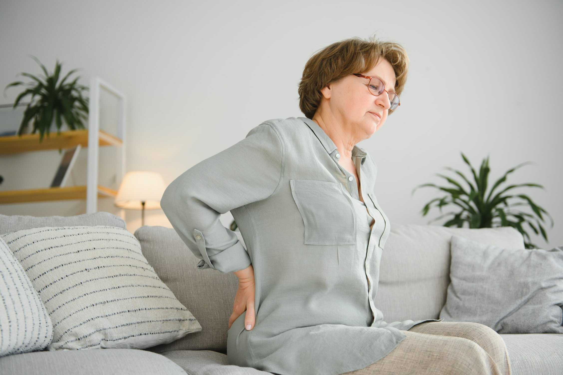 a woman sitting on a couch with her chronic back pain