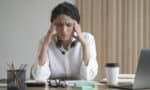 a woman with headphones holding her temples because of neck pain and headaches